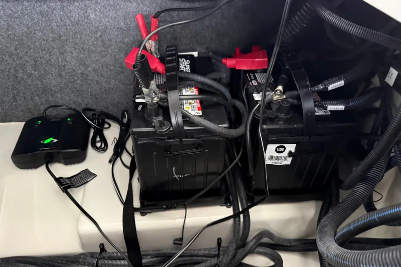 Slide: The Image of 2022 Yamaha Boats 252SD battery compartment with cables and charger connections. - 27