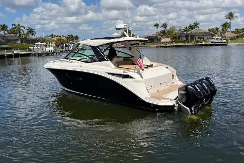 Slide: The Image of 2020 Sea Ray Sundancer 320 Outboard cruising on a sunny day, featuring triple Mercury engines. - 2