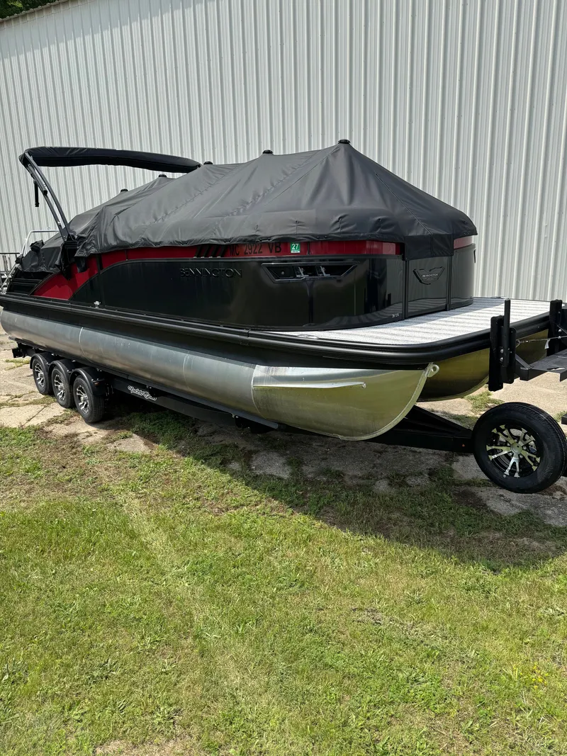 Slide: The Image of A 2025 Bennington 26LXSSB pontoon boat on a trailer, featuring a black cover and red accent. - 2