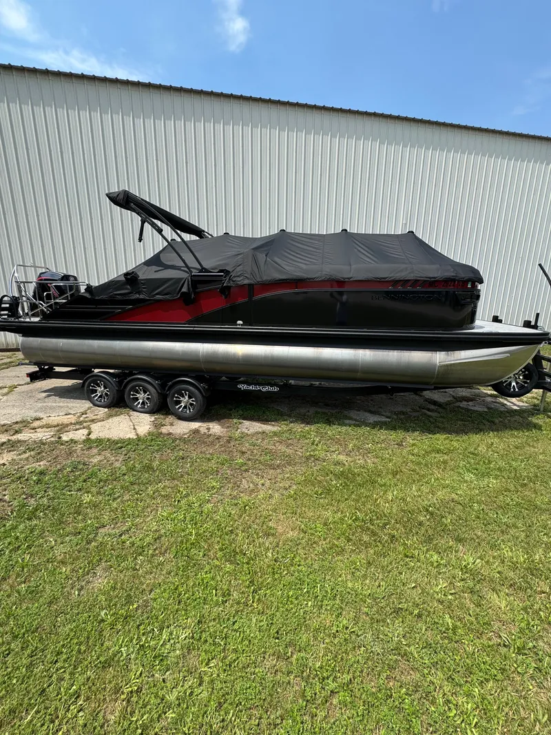 Slide: The Image of A 2025 Bennington 26LXSSB on a trailer, parked in front of a large building. - 3