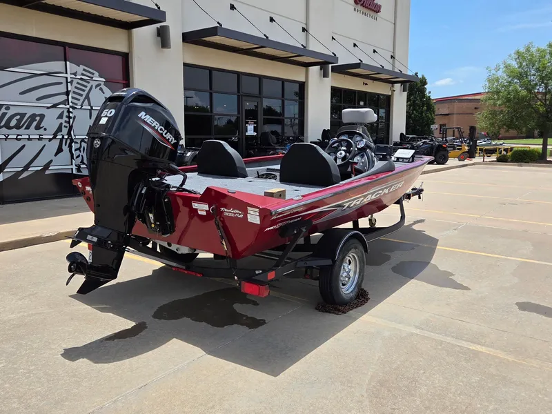 Slide: The Image of A red Tracker boat on a trailer parked in front of a building. - 8