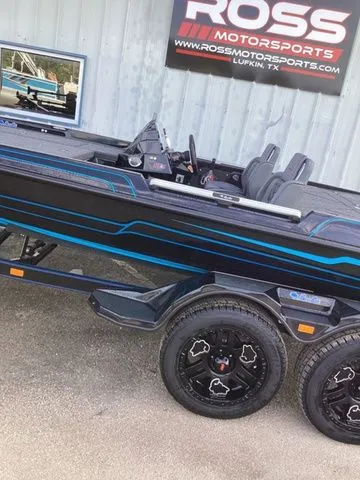 Slide: The Image of A 2026 Bass Cat Lynx STS on a trailer in front of a building with a sign. - 15