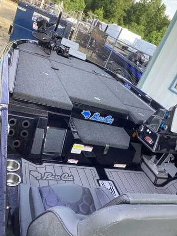 Slide: The Image of The image shows the deck of a Bass Cat Lynx STS boat with gray upholstery and storage. - 13