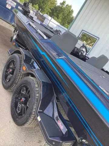 Slide: The Image of A 2026 Bass Cat Lynx STS boat on a trailer, featuring blue accents and modern wheels. - 8