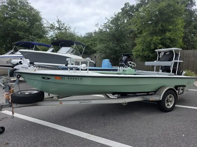 The Image of A 2003 Hells Bay Marquesa boat on a trailer, surrounded by other boats and trees. - 1