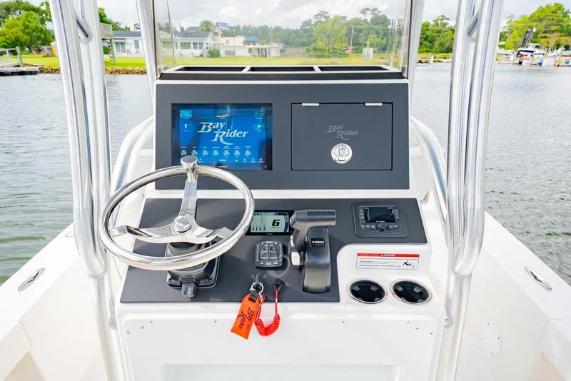 Slide: The Image of 2026 Bay Rider 219 Bay boat console with steering wheel and control panel on water. - 14