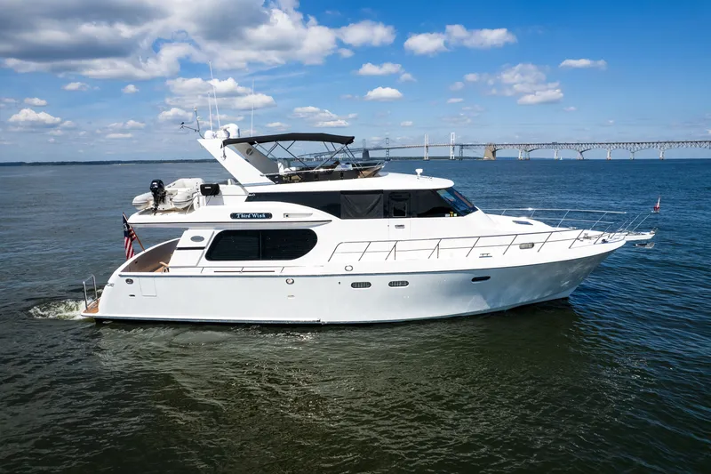Slide: The Image of Luxury yacht Symbol 56, 2003 model, cruising on open water with bridge in background. - 11