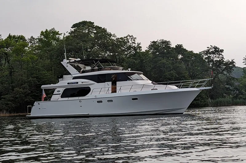 The Image of A 2003 Symbol 56 yacht anchored on a calm lake with lush trees. - 1