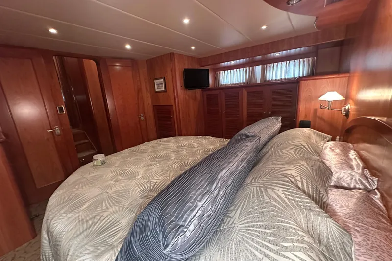 Slide: The Image of Luxurious bedroom interior on a 2003 Symbol 56 yacht, featuring wood paneling and elegant bedding. - 47