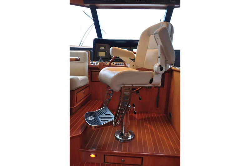 Slide: The Image of Captain's chair in a 2003 Symbol 56 yacht cockpit, featuring wood flooring and navigation equipment. - 17