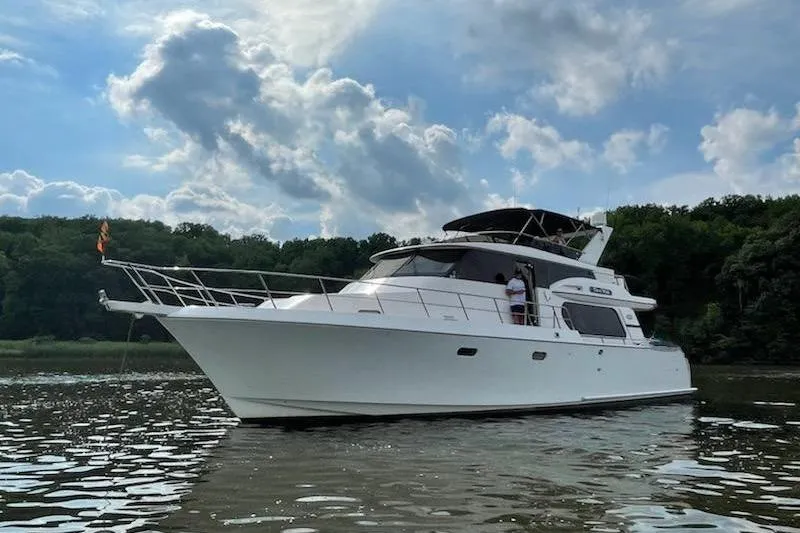 Slide: The Image of Luxury Symbol 56 yacht from 2003 on calm water under a partly cloudy sky. - 2