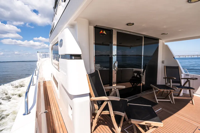 Slide: The Image of Luxurious 2003 Symbol 56 yacht deck with chairs, cruising on open water under blue skies. - 16