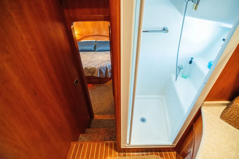 Slide: The Image of Luxurious yacht interior with wooden finish, featuring a cozy bedroom and modern shower area. - 83