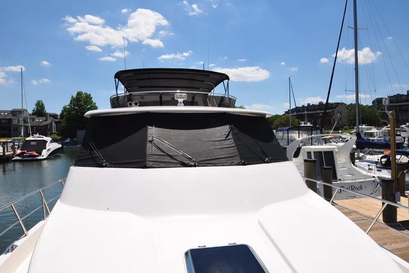 Slide: The Image of Luxury yacht Symbol 56, 2003 model, docked at marina under clear blue sky. - 13