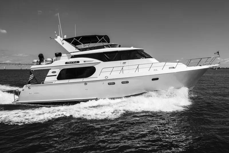 Slide: The Image of A 2003 Symbol 56 yacht cruising on open water, with a bridge in the background. - 13