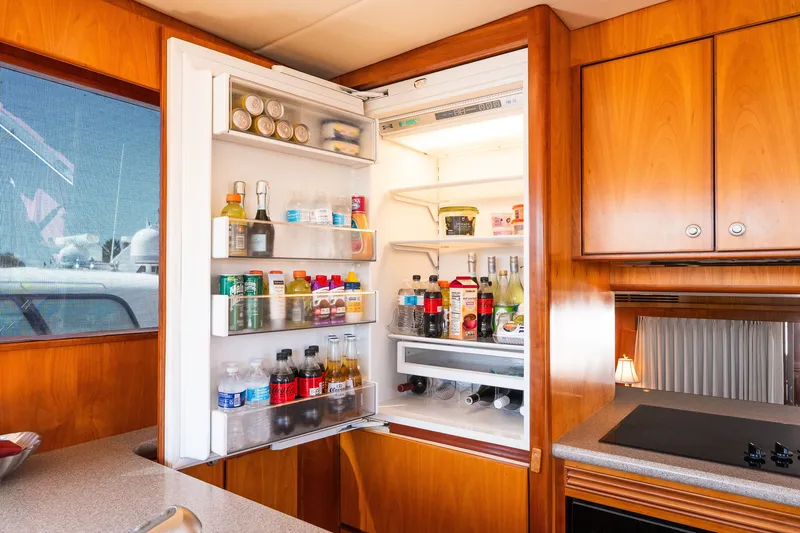 Slide: The Image of Open refrigerator in a yacht kitchen, stocked with beverages and food, wooden cabinetry, Symbol 56, 2003. - 65