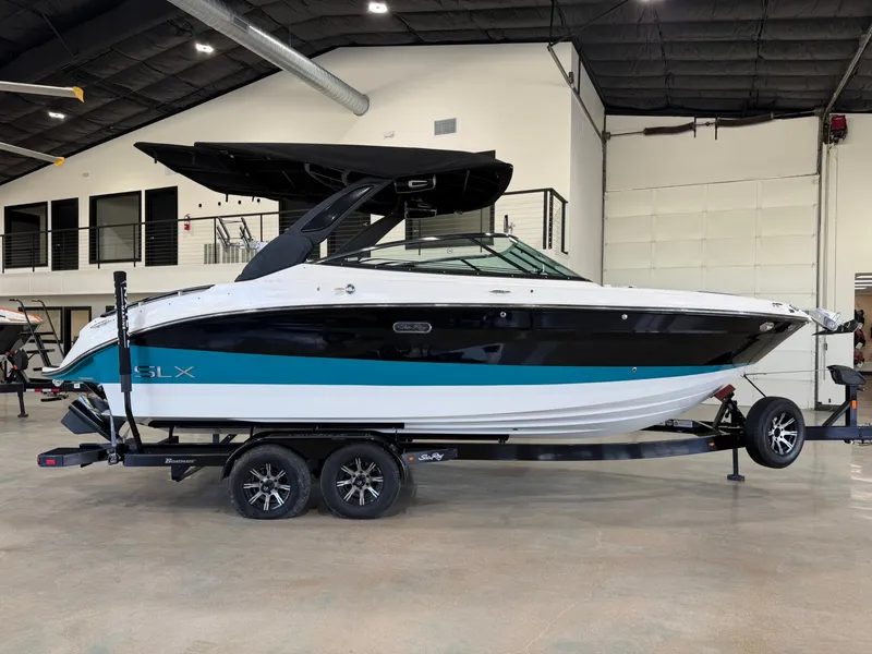 Slide: The Image of A 2024 Sea Ray SLX 260 Surf boat on a trailer inside a showroom. - 2