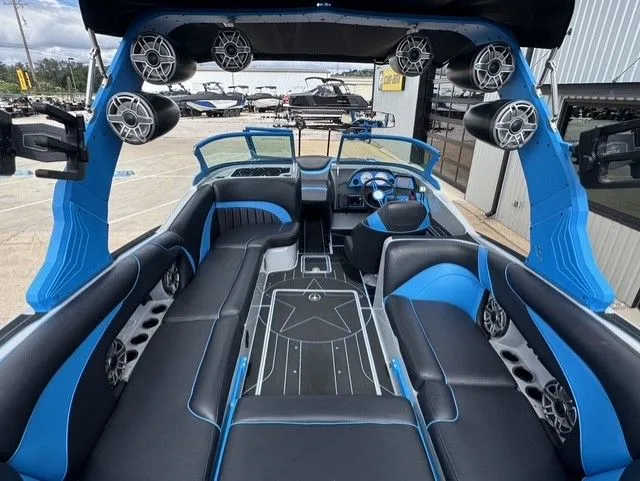 Slide: The Image of The image shows the interior of a 2023 MB SPORTS B52 23 Alpha boat. It features black and blue upholstery with speakers and cup holders. - 12