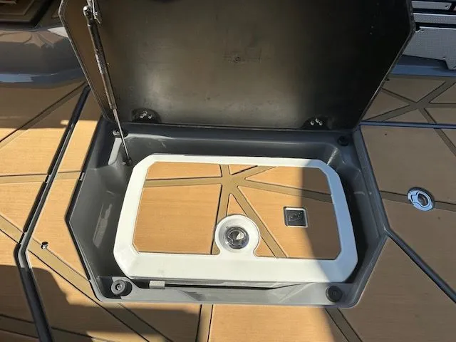 Slide: The Image of An open storage compartment on a boat with wooden flooring and a white insert. - 34
