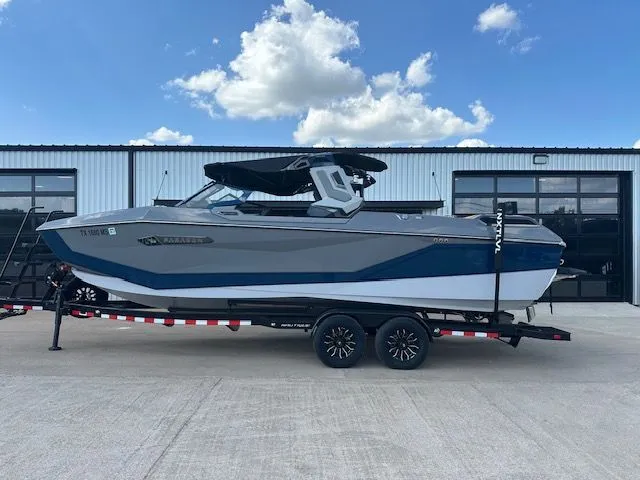 The Image of A modern motorboat with blue and white paint sits on a trailer in front of a building. - 1
