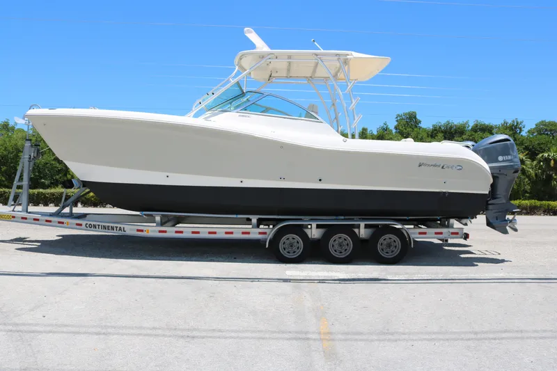 Slide: The Image of 2014 World Cat 295 DC boat on trailer, side view, under clear blue sky. - 2