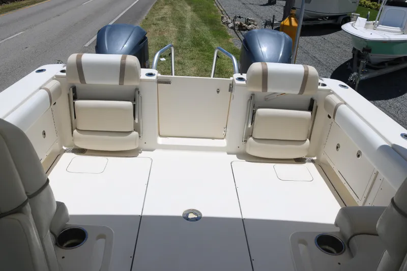 Slide: The Image of 2014 World Cat 295 DC boat interior with seating and twin engines, parked near a road. - 11