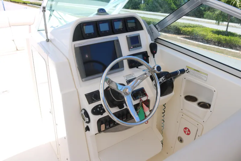 Slide: The Image of 2014 World Cat 295 DC boat helm with steering wheel and navigation controls. - 5