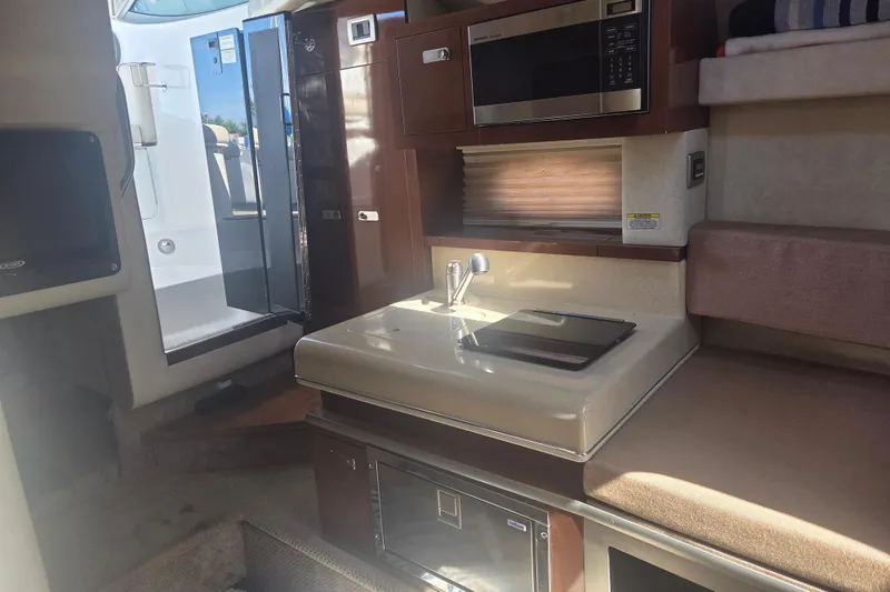 Slide: The Image of Interior of a 2012 Sea Ray Sundancer 260 boat, featuring a compact kitchenette. - 13