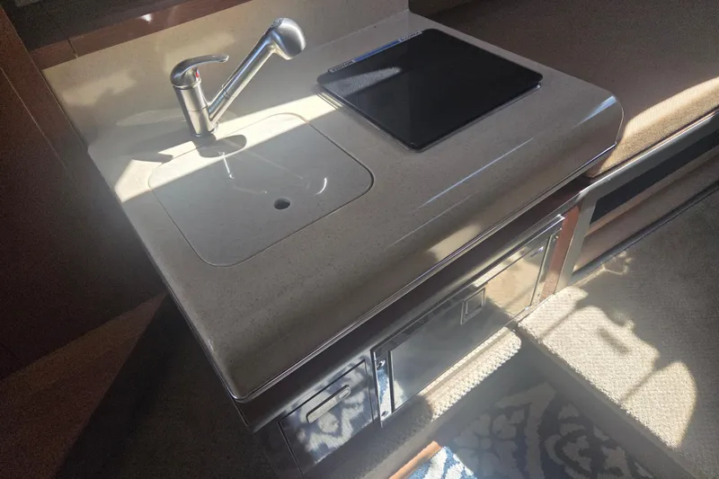 Slide: The Image of Interior of 2012 Sea Ray Sundancer 260 showing a compact kitchenette with sink and stove. - 15