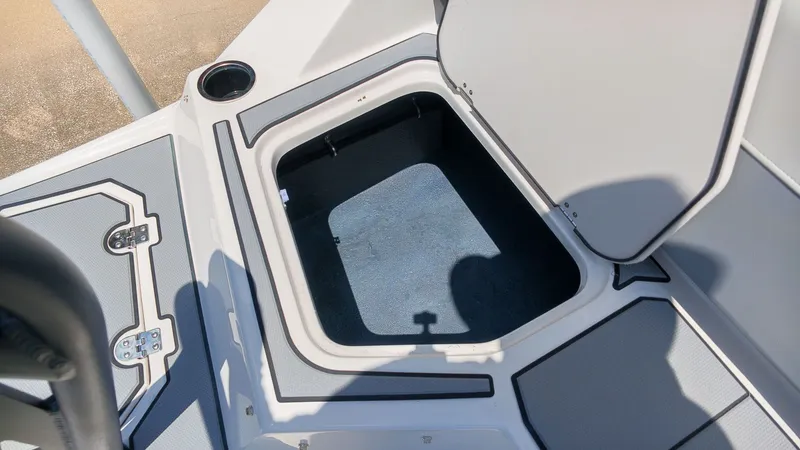Slide: The Image of An open storage compartment on a boat with gray flooring and a cup holder. - 8