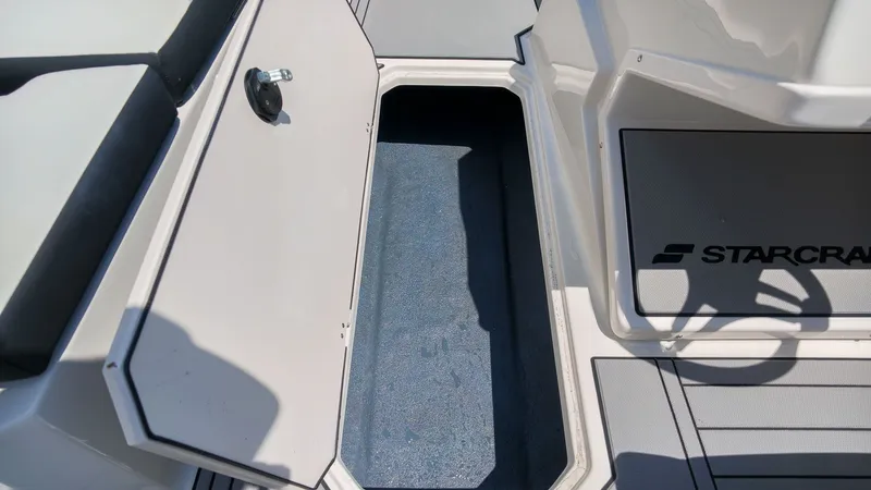 Slide: The Image of An open storage compartment on a Starcraft boat with gray flooring. - 9
