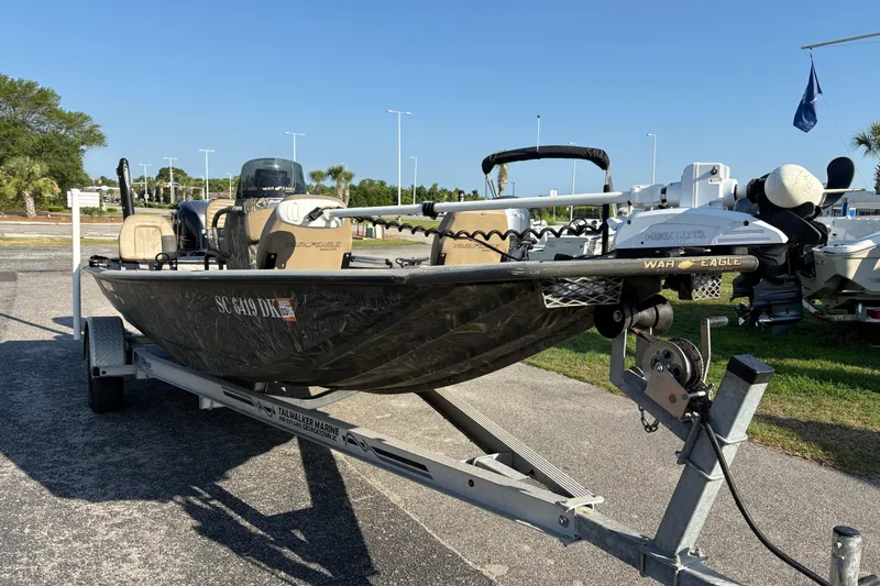 Slide: The Image of 2019 War Eagle 961 Blackhawk boat on trailer, parked outdoors under clear blue sky. - 4