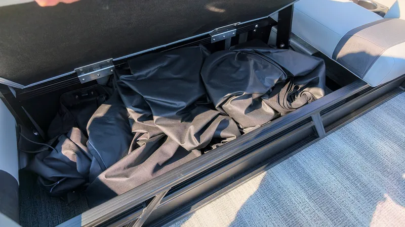 Slide: The Image of An open storage compartment on a boat reveals black covers or tarps. - 11
