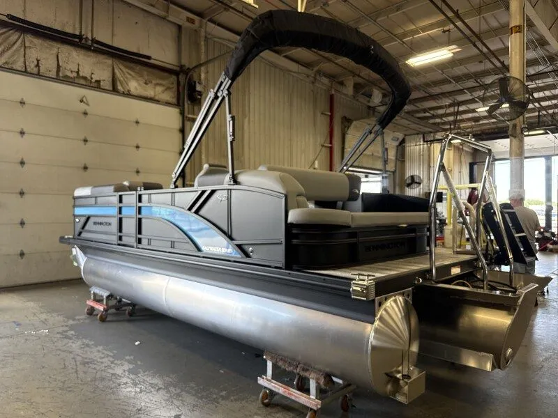 The Image of Bennington 21 S Swingback pontoon boat in a warehouse, featuring gray seating and black railing. - 1