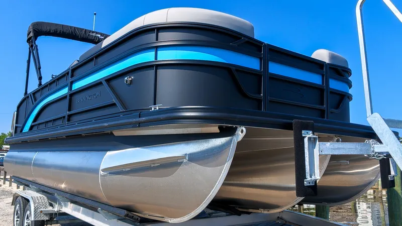 Slide: The Image of A 2027 Bennington 21 S Swingback pontoon boat on a trailer, featuring a blue and black design. - 2