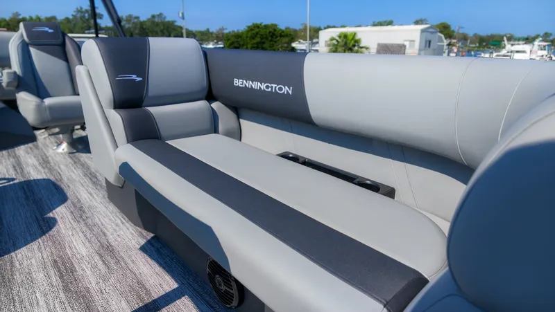 Slide: The Image of The image shows a gray and black bench seat on a Bennington boat, surrounded by a wooden deck. - 13