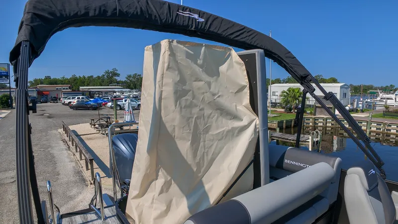 Slide: The Image of A Bennington 21 S Swingback pontoon boat with black Bimini top and beige curtain at the dock. - 7