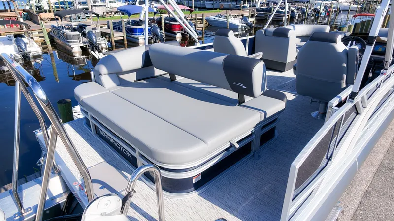 Slide: The Image of The image shows a 2027 Bennington 22 S Swingback pontoon boat with gray upholstery at a marina. - 6
