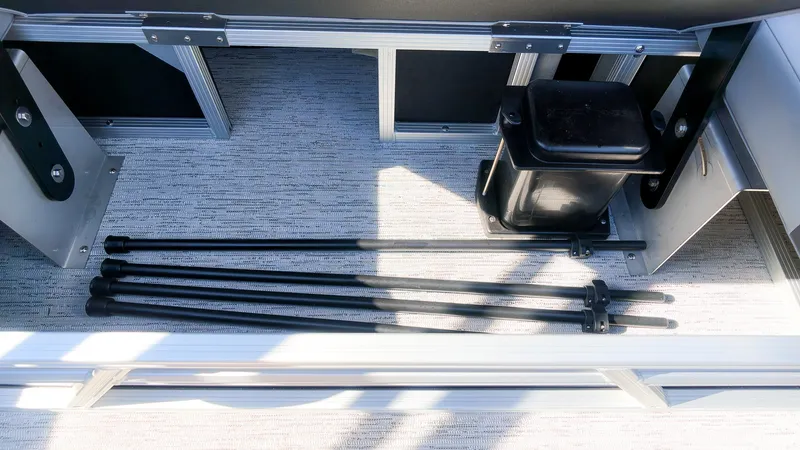 Slide: The Image of A storage compartment in the boat with several black poles and a black container. - 10