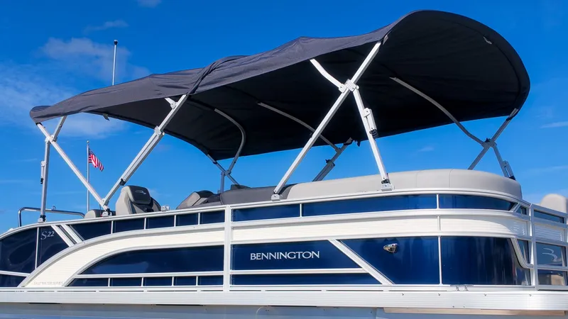 Slide: The Image of A sleek Bennington 22 S Swingback pontoon boat with a blue hull and black sunshade. - 22