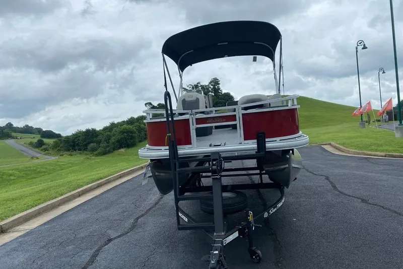 Slide: The Image of 2026 Sun Tracker Bass Buggy 18 DLX pontoon boat on trailer, parked on paved road. - 2