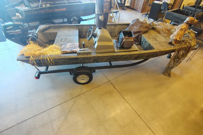 The Image of 2026 Tracker Grizzly 1648 SC boat with Mercury engine, camo design, and hunting gear. - 0