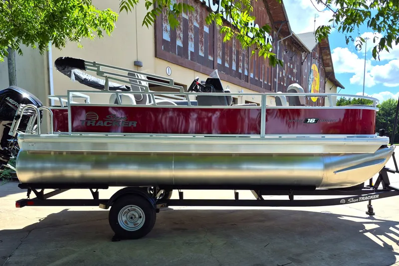 Slide: The Image of 2026 Sun Tracker Bass Buggy 18 DLX pontoon boat on trailer, parked outdoors. - 4