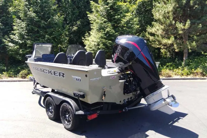 Slide: The Image of 2026 Tracker Targa V-18 Combo boat on trailer, parked outdoors with trees in background. - 2