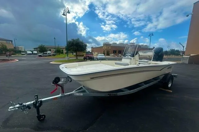 Slide: The Image of 2026 Mako Pro Skiff 17 CC boat on trailer in parking lot under cloudy sky. - 2