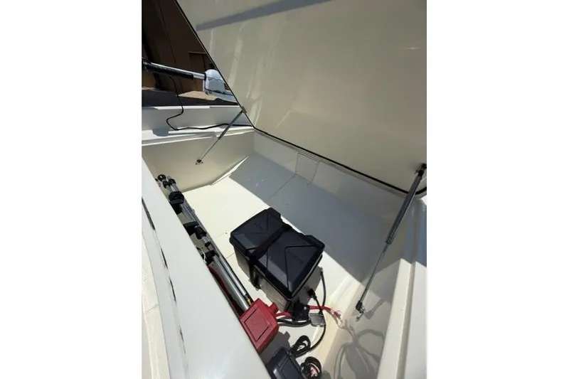 Slide: The Image of 2026 Mako Pro Skiff 17 CC boat storage compartment with equipment and battery. - 11