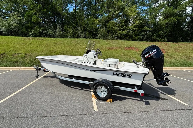 Slide: The Image of 2026 Mako Pro Skiff 15 CC boat on trailer, parked in a lot with grassy background. - 3