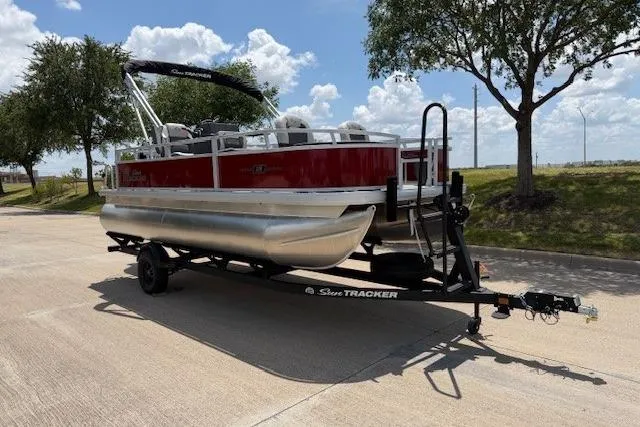 Slide: The Image of 2026 Sun Tracker Bass Buggy 18 DLX pontoon boat on trailer, parked outdoors. - 3