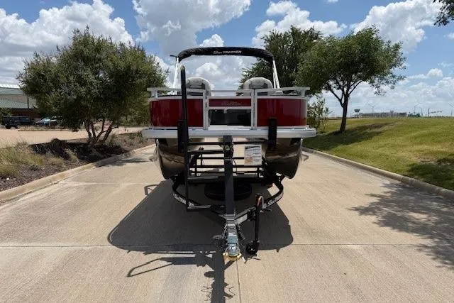 Slide: The Image of 2026 Sun Tracker Bass Buggy 18 DLX pontoon boat on trailer, parked on sunny road. - 6