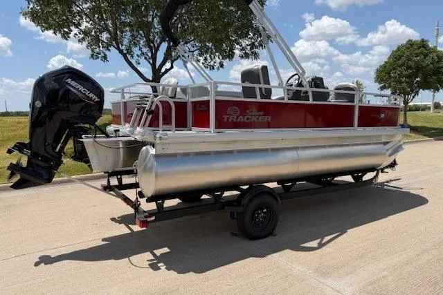 Slide: The Image of 2026 Sun Tracker Bass Buggy 18 DLX pontoon boat on trailer, parked outdoors. - 4